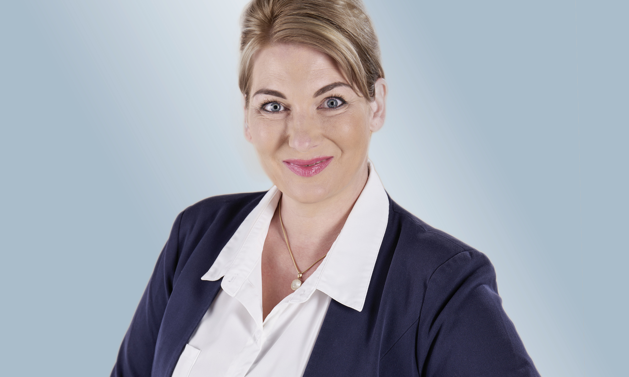 Bürgermeisterkandidatin Verena Beese vor einer hellblauen Fläche. Ihre Haare sind hochgesteckt, sie trägt einen dunkelblauen Blazer und eine weiße Bluse. Foto: Gregor Eisele - Kaloo Images